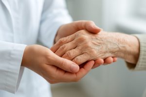 A close-up of a caregiver's hands gently holding an elderly person's hands, symbolizing support and care.